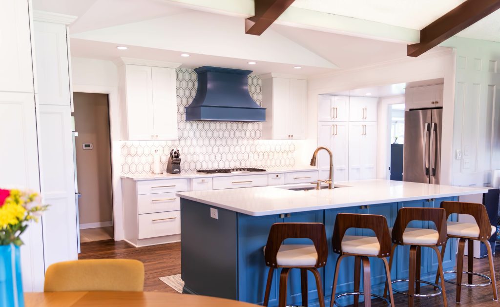Bright modern kitchen with a blue island and white cabinets.